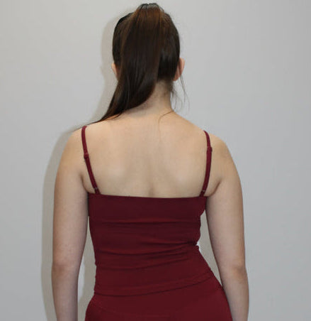 Person wearing a red tank top and shorts standing on a white background