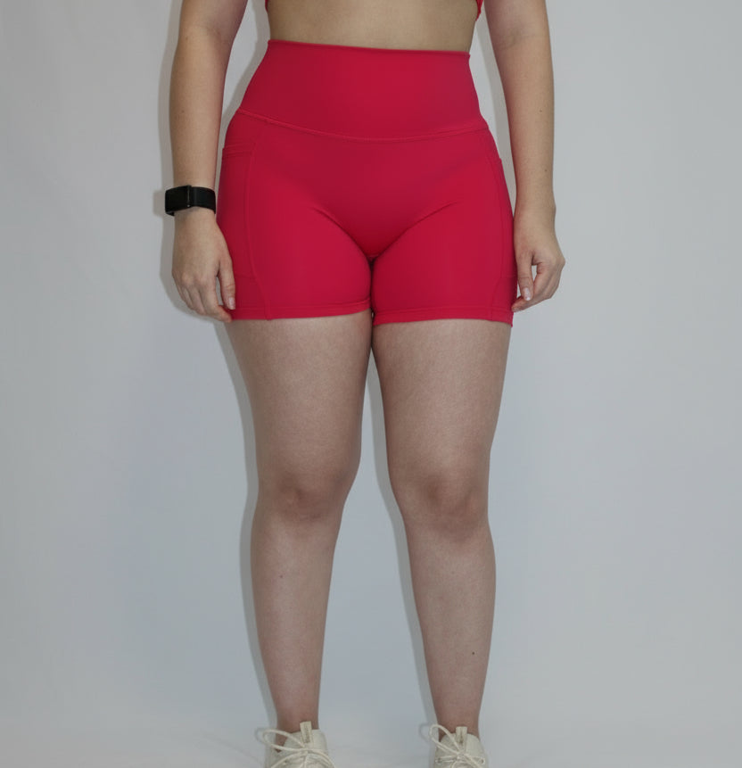 Person wearing a pink sports bra and shorts on a white background