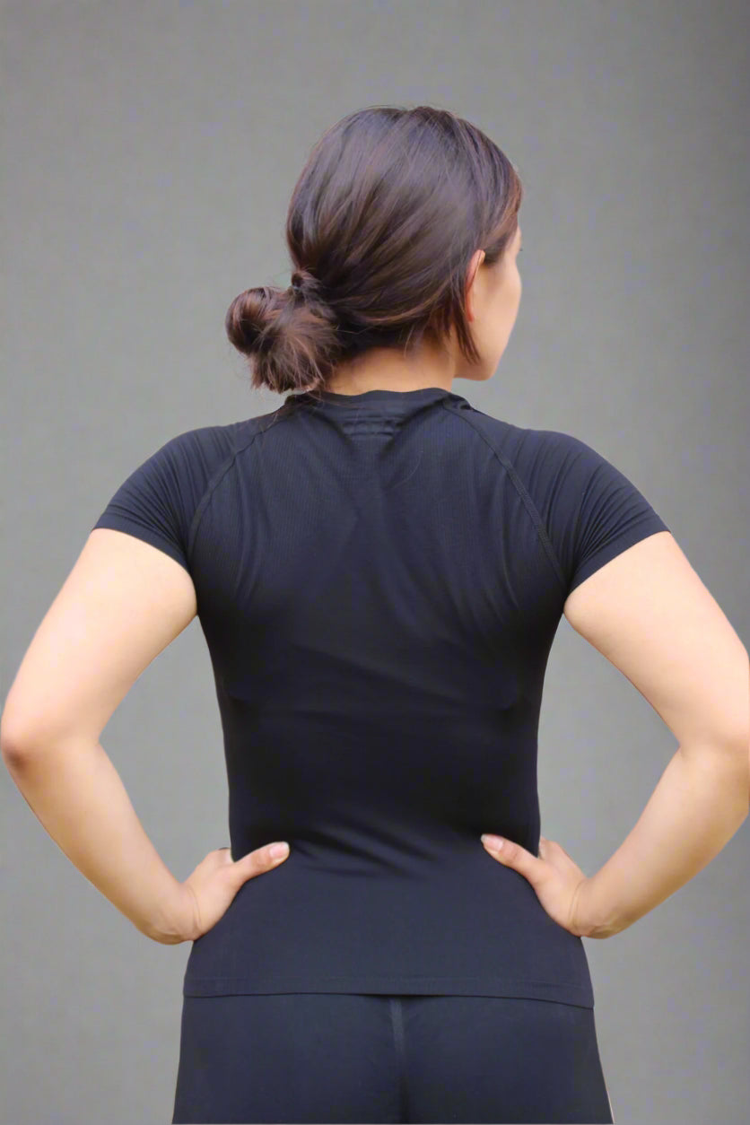 Person wearing a black athletic outfit standing against a brick wall