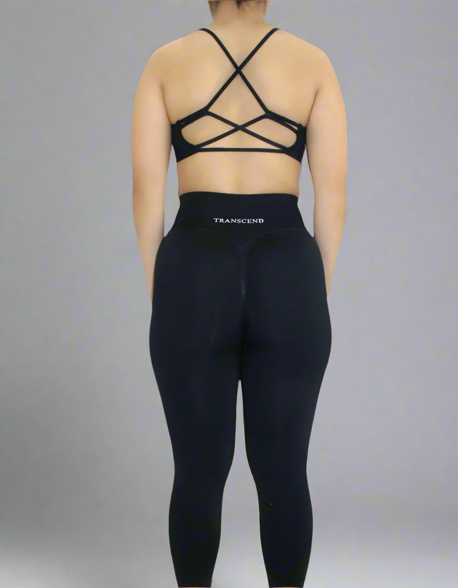 woman wearing athletic black bra and legging with logo on white background