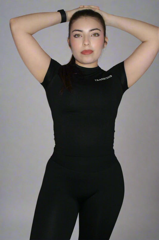 Person wearing a black athletic outfit with a logo on a plain background