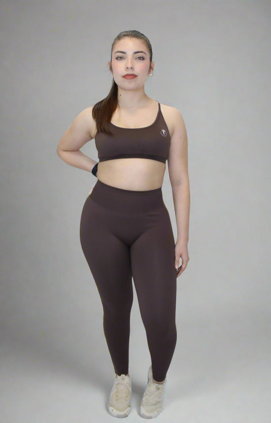 Woman wearing a brown sports bra and leggings set on a white background